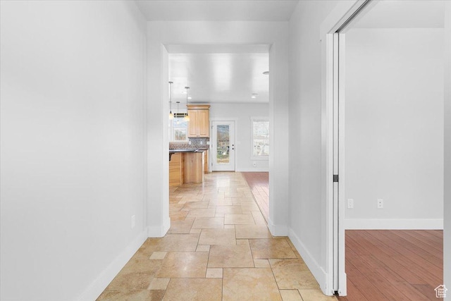 hallway with stone finish flooring and baseboards