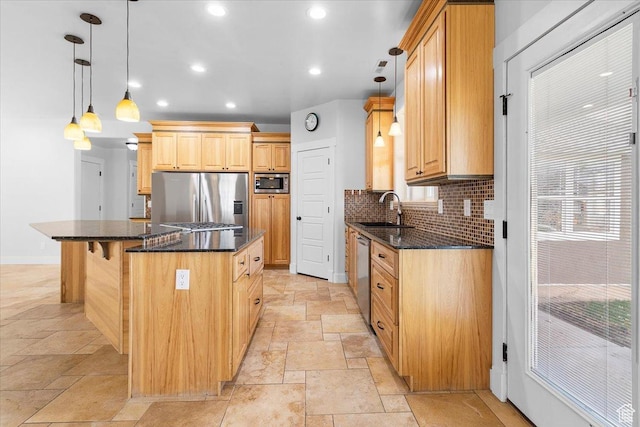 kitchen featuring a center island, a sink, appliances with stainless steel finishes, stone tile floors, and decorative backsplash