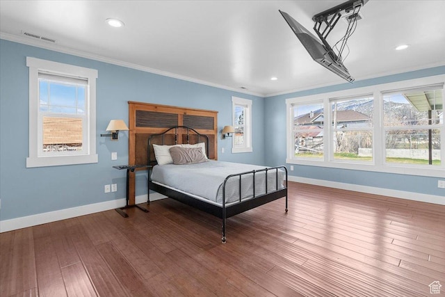bedroom featuring baseboards, crown molding, visible vents, multiple windows, and hardwood / wood-style flooring