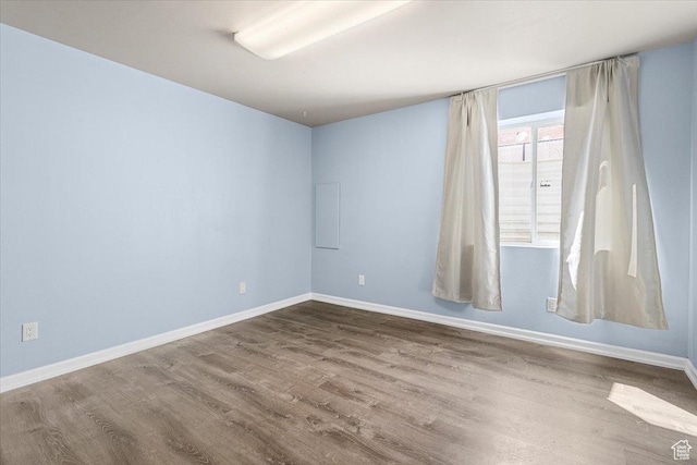 spare room featuring dark wood-type flooring and baseboards