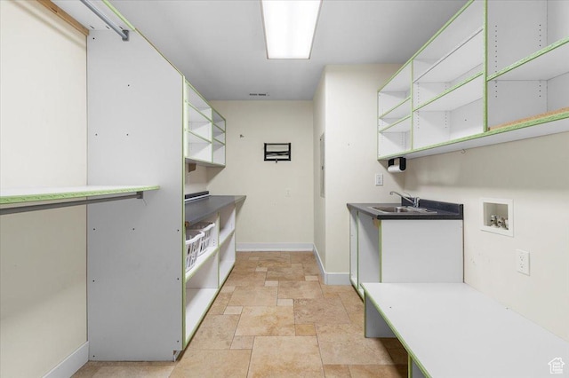 kitchen featuring open shelves, stone finish flooring, visible vents, a sink, and baseboards