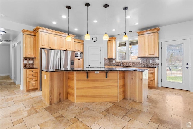 kitchen featuring stone tile floors, a spacious island, light brown cabinets, and stainless steel appliances