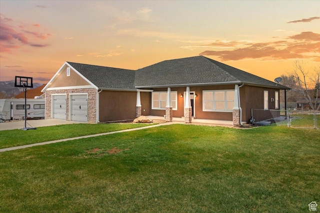 view of front of property with fence, stone siding, a garage, and a lawn