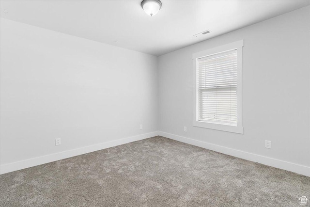 carpeted empty room featuring baseboards and visible vents