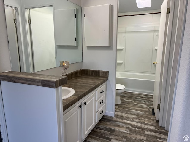 bathroom featuring a skylight, vanity, toilet, and wood finished floors