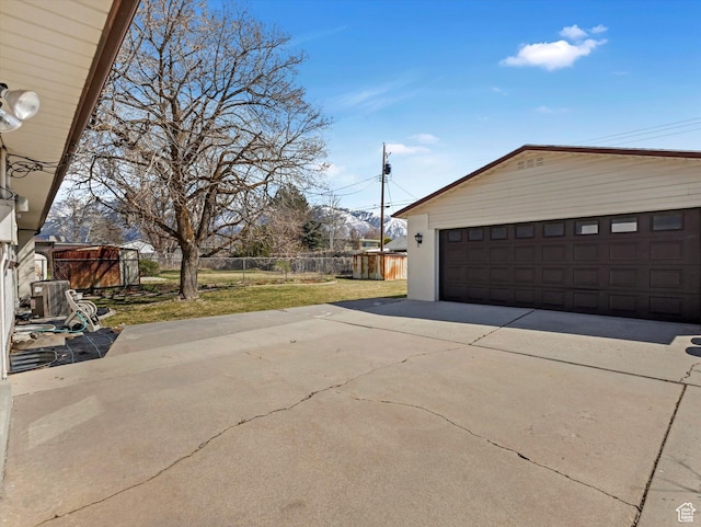detached garage featuring central AC unit and fence