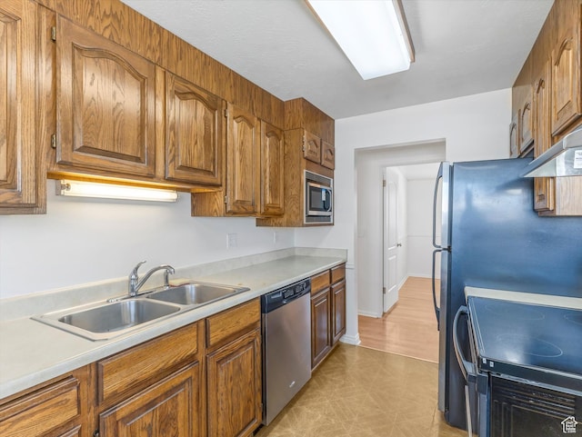 kitchen featuring a sink, light countertops, appliances with stainless steel finishes, and brown cabinets
