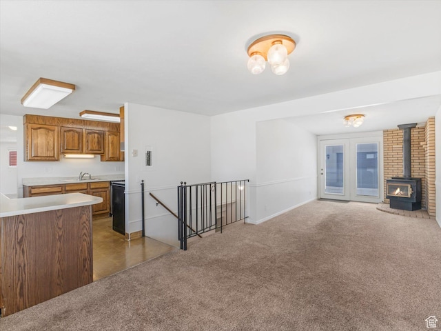kitchen with a wood stove, brown cabinetry, carpet flooring, light countertops, and open floor plan
