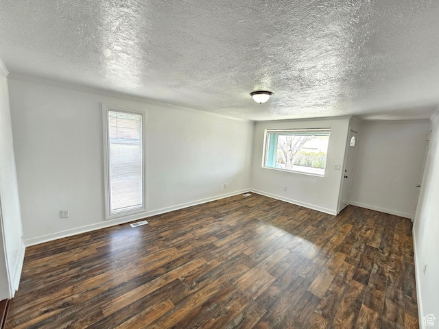 unfurnished room featuring a textured ceiling, dark wood-style flooring, baseboards, and visible vents