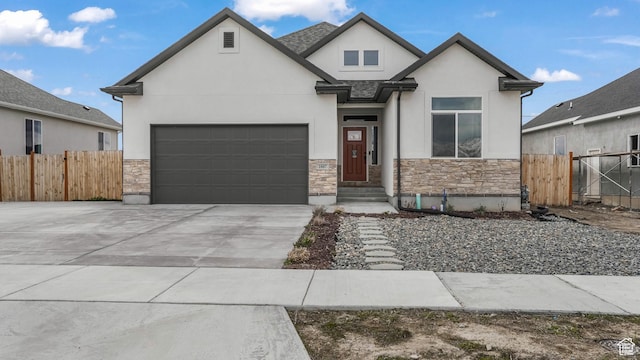 view of front of home with stucco siding, driveway, stone siding, a garage, and fence