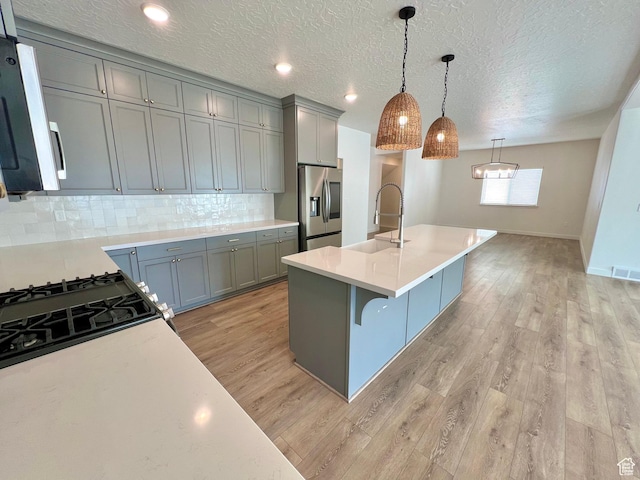 6293 W Jackson Crest Way, Herriman, UT 84096 - kitchen with light wood-type flooring, appliances with stainless steel finishes, light countertops, a sink, and backsplash
