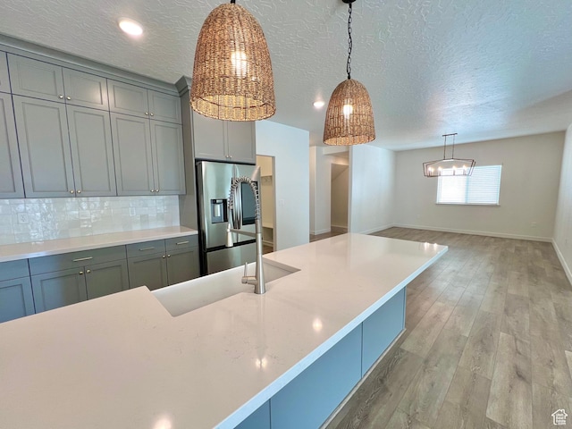 6293 W Jackson Crest Way, Herriman, UT 84096 - kitchen featuring stainless steel fridge with ice dispenser, light countertops, decorative light fixtures, light wood finished floors, and backsplash