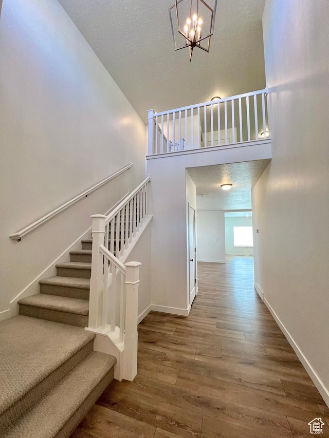 6293 W Jackson Crest Way, Herriman, UT 84096 - stairs featuring baseboards, a towering ceiling, a chandelier, and wood finished floors