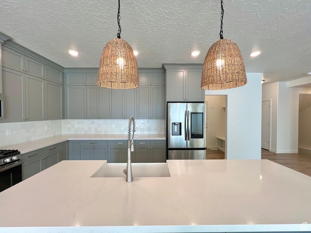 6293 W Jackson Crest Way, Herriman, UT 84096 - kitchen with gray cabinets, decorative backsplash, a sink, and stainless steel refrigerator with ice dispenser
