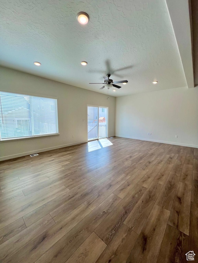 6293 W Jackson Crest Way, Herriman, UT 84096 - unfurnished living room featuring visible vents, baseboards, wood finished floors, and a textured ceiling