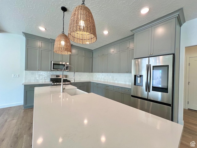 6293 W Jackson Crest Way, Herriman, UT 84096 - kitchen featuring gray cabinets, backsplash, light wood-style flooring, and appliances with stainless steel finishes