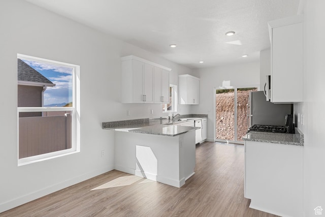7129 Oquirrh Ranch Pkwy N, Eagle Mountain, UT 84005 - kitchen featuring light wood finished floors, white cabinetry, a sink, and light stone counters