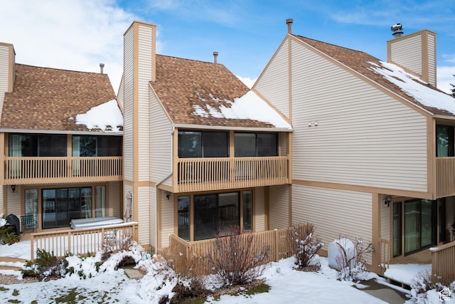 snow covered rear of property featuring a chimney
