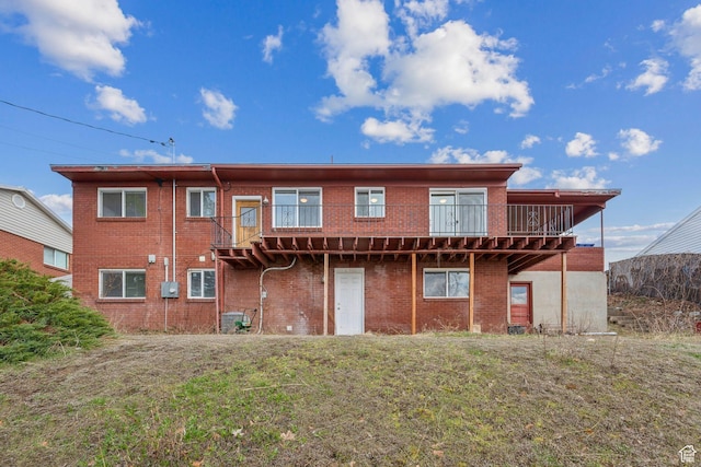 back of house with brick siding, a deck, and a yard