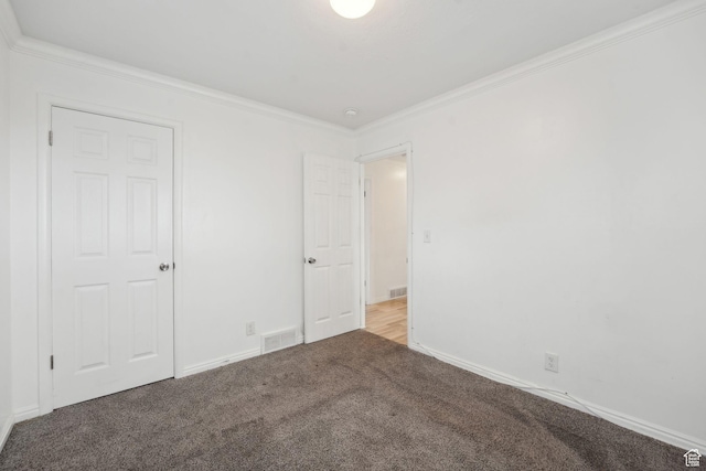 carpeted empty room featuring crown molding, visible vents, and baseboards