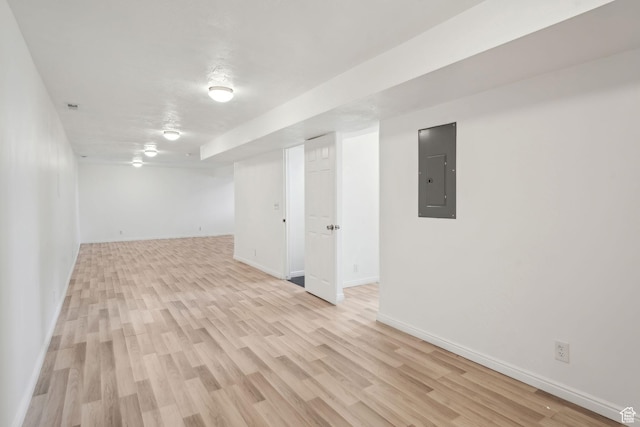 spare room with baseboards, light wood finished floors, and electric panel