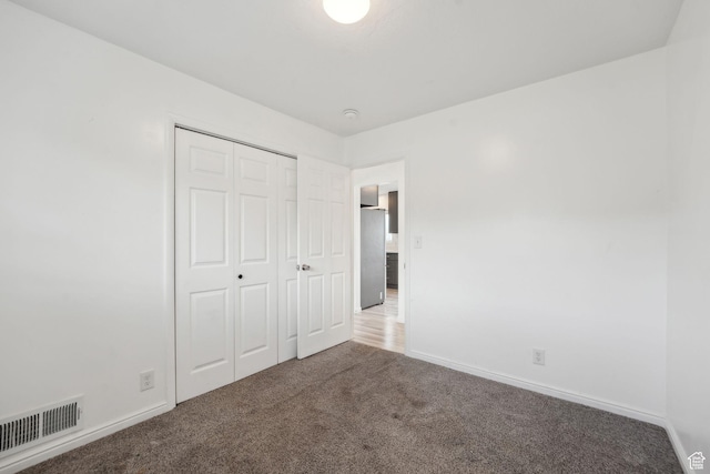 unfurnished bedroom featuring carpet flooring, visible vents, a closet, and baseboards