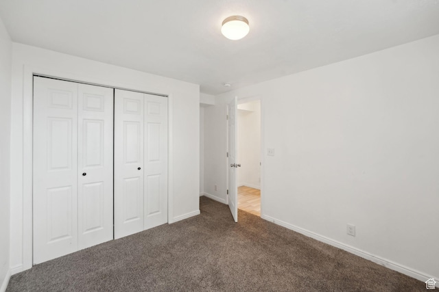 unfurnished bedroom featuring a closet, dark colored carpet, and baseboards