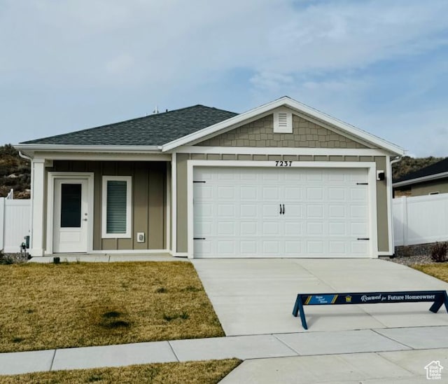 view of front of house with a shingled roof, concrete driveway, a garage, and fence