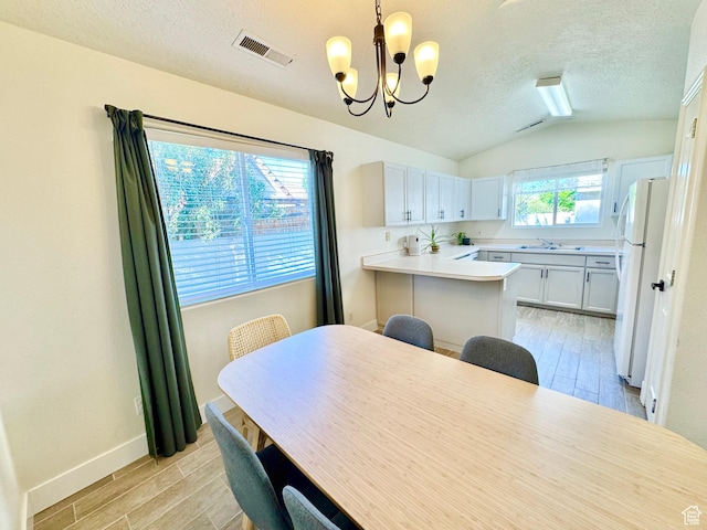 dining space featuring visible vents, an inviting chandelier, wood finish floors, and lofted ceiling