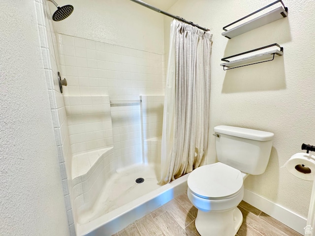full bathroom featuring toilet, a stall shower, a textured wall, and wood tiled floor