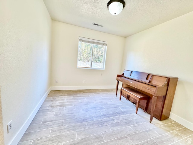 living area with visible vents, baseboards, and a textured ceiling