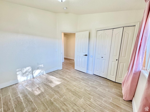 unfurnished bedroom featuring baseboards, vaulted ceiling, and wood tiled floor