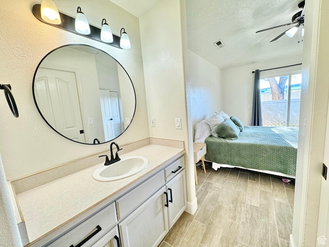ensuite bathroom featuring connected bathroom, a textured ceiling, a ceiling fan, visible vents, and wood finished floors