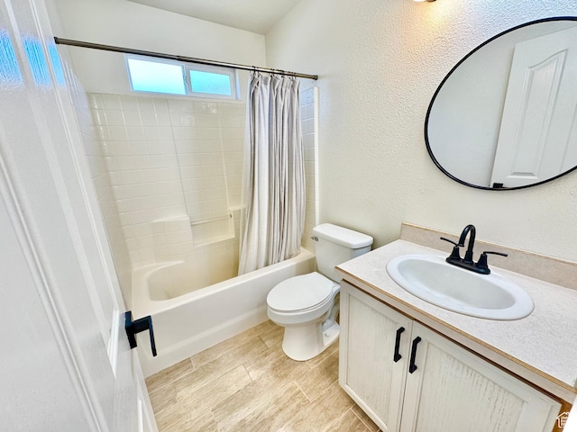 bathroom with a textured wall, shower / bathtub combination with curtain, vanity, and toilet