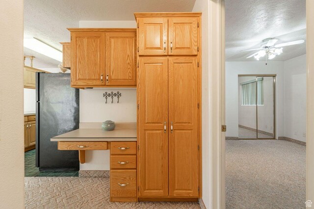 1050 W Red Hills Pkwy Unit 125, Washington, UT 84780 - kitchen with light countertops, freestanding refrigerator, a textured ceiling, ceiling fan, and light colored carpet