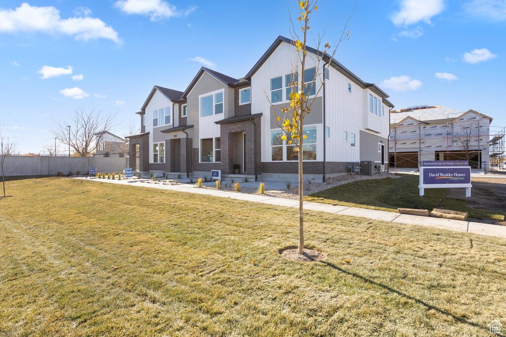 view of front of home featuring a front yard, brick siding, cooling unit, and fence