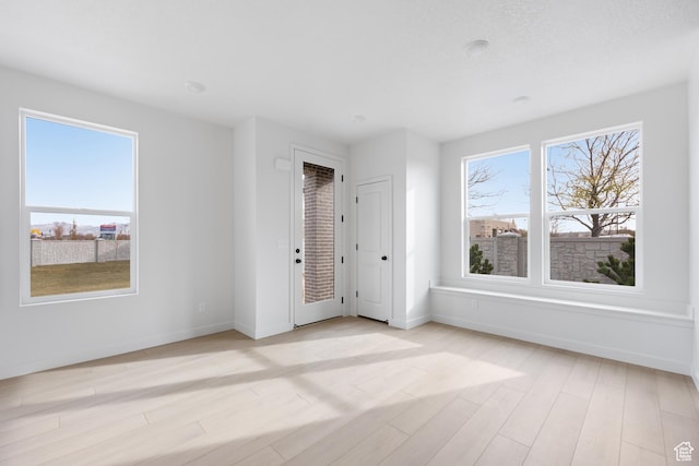 unfurnished room with light wood-style flooring and baseboards