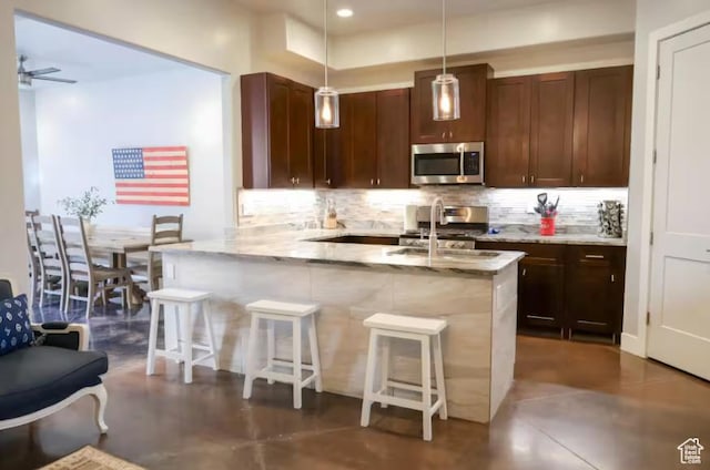 4277 W Canterbury Rd, Hurricane, UT 84737 - kitchen with stainless steel microwave, tasteful backsplash, stove, and a kitchen breakfast bar