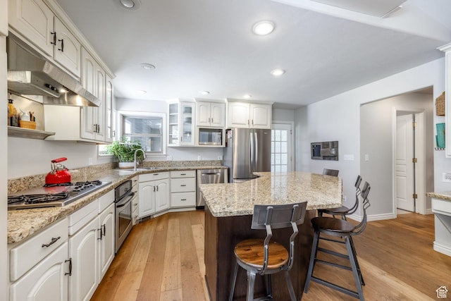 9106 N Upper Lando Ln, Park City, UT 84098 - kitchen with stainless steel appliances, under cabinet range hood, light wood-type flooring, a kitchen breakfast bar, and a center island