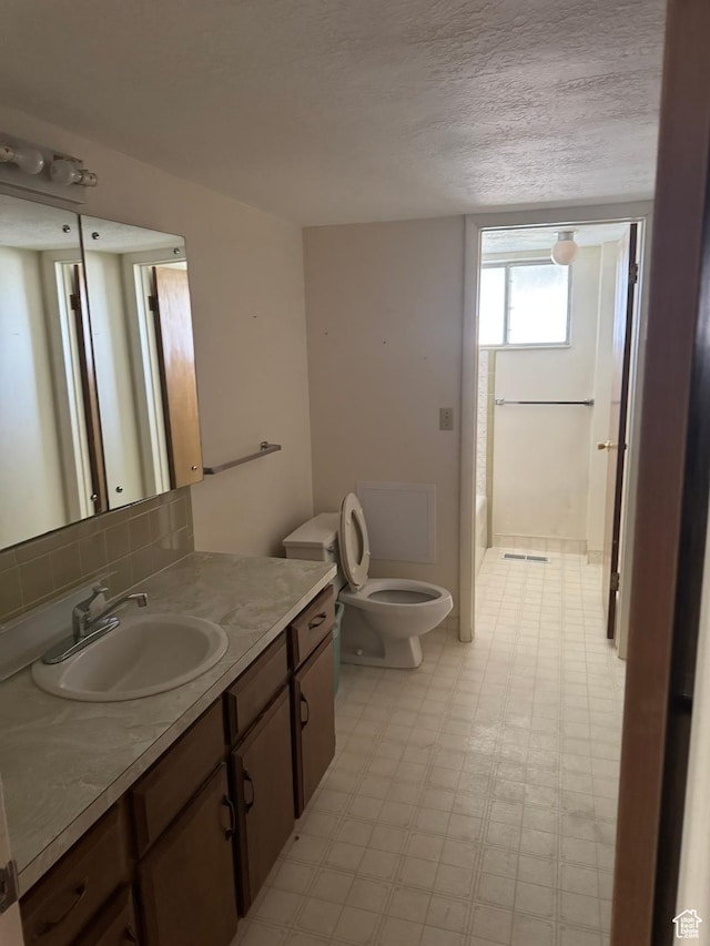 871 N Bonita Way E Unit 19, Centerville, UT 84014 - full bathroom featuring a textured ceiling, vanity, toilet, tile patterned floors, and backsplash