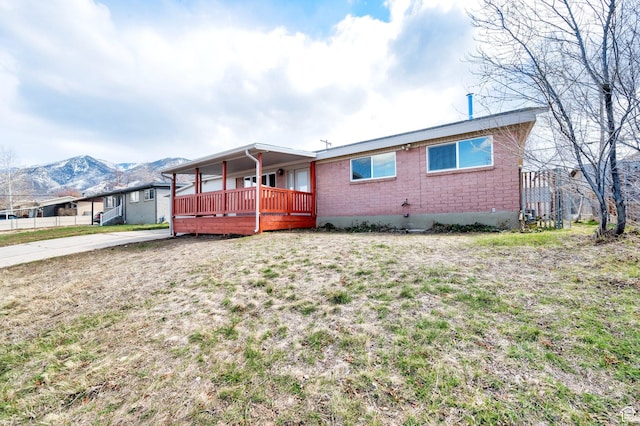 684 E Oquirrh Ave N, Tooele, UT 84074 - rear view of property featuring a deck with mountain view, a yard, brick siding, and driveway