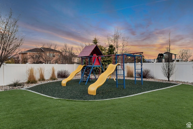 playground at dusk with a playground, a lawn, and fence private yard