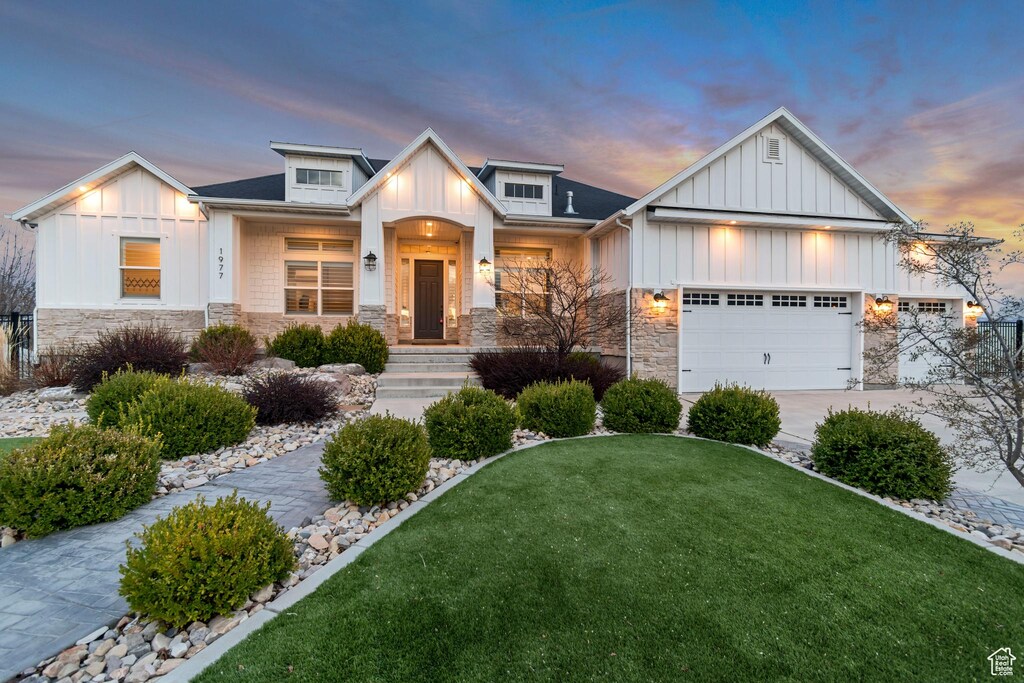 1977 W Olympus Peak Cir, West Jordan, UT 84088 - view of front facade featuring board and batten siding, a garage, stone siding, a front lawn, and concrete driveway