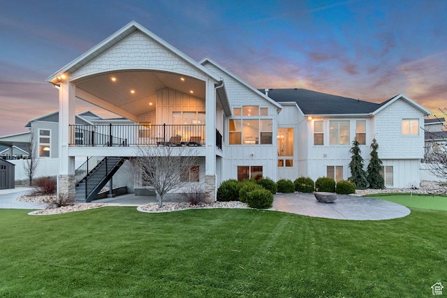 back of house at dusk featuring a patio, stairway, and a lawn