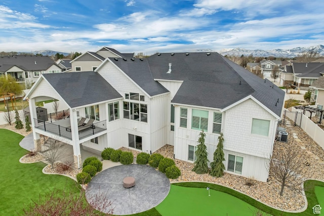 rear view of house with a patio, a shingled roof, a residential view, and central AC