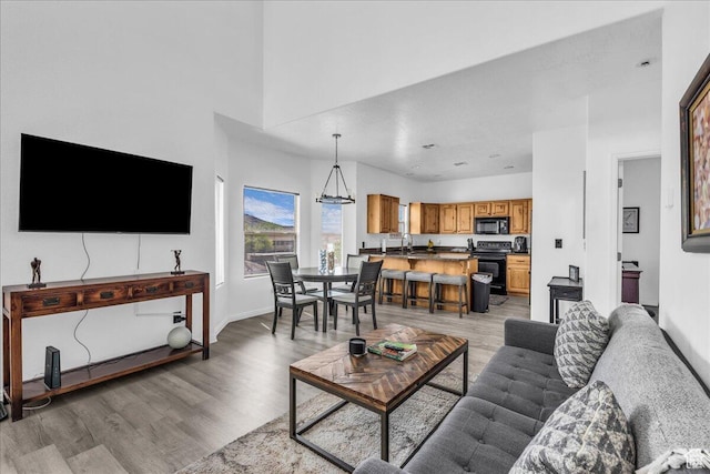 1277 W Las Hurdes Dr, St George, UT 84770 - living room featuring baseboards, light wood finished floors, a notable chandelier, and a towering ceiling