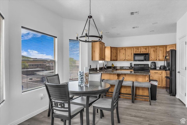 1277 W Las Hurdes Dr, St George, UT 84770 - kitchen featuring light wood-style flooring, a peninsula, black appliances, a sink, and a notable chandelier
