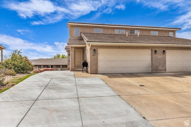 view of front facade with a tiled roof, concrete driveway, stucco siding, and a garage