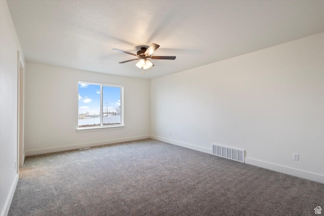 carpeted spare room with visible vents, ceiling fan, and baseboards