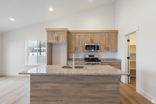 kitchen featuring light stone counters, recessed lighting, light wood-style flooring, appliances with stainless steel finishes, and a sink